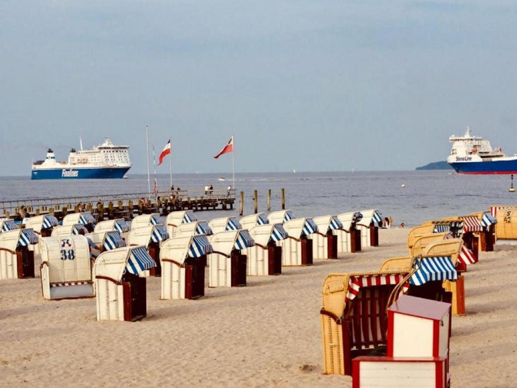 a beach with many beach chairs and two cruise ships at Strand Suite in Lübeck