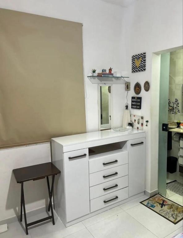 een witte badkamer met een wastafel en een kruk bij Quarto Suite Barra Réveillon Salvador in Salvador