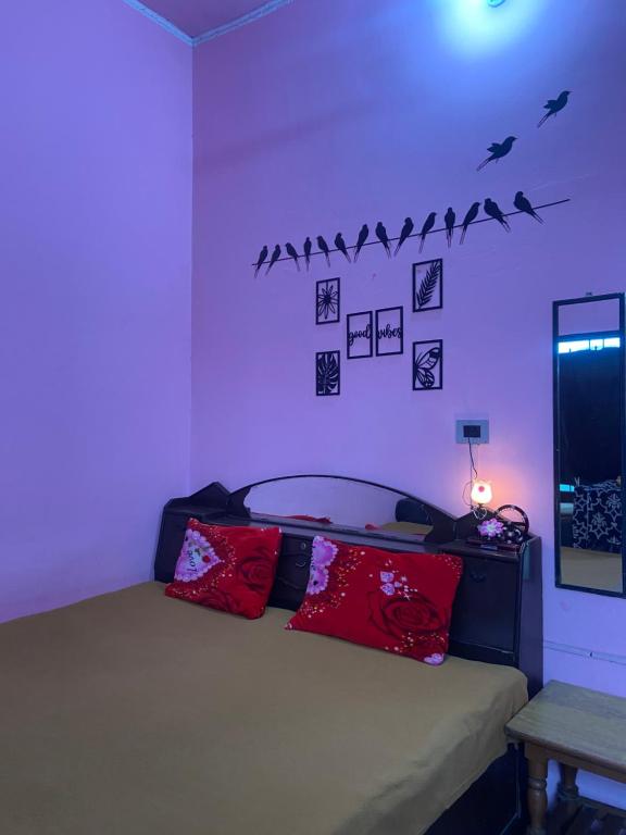 ein Schlafzimmer mit einem Bett mit roten Kissen und Vögeln an der Wand in der Unterkunft Hillsview Homestay in Rūpnagar