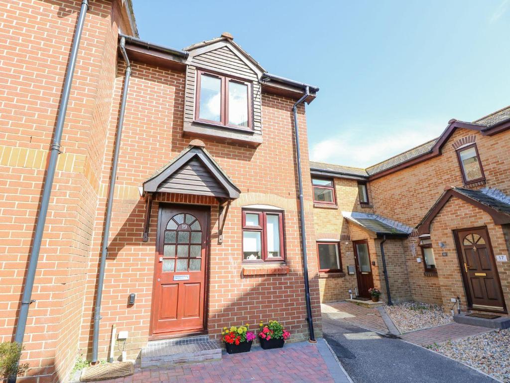 a brick building with a red door and some flowers at Harbour View Poole in Poole