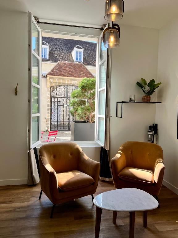 a living room with two chairs and a large window at Le Laurencin Sens - Le Keys - Cœur de ville in Sens