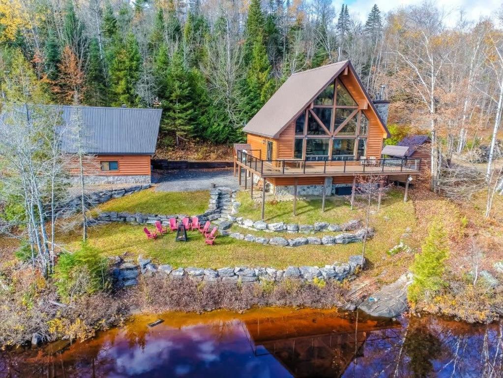 an aerial view of a log cabin with a pond at Le Tresor du Lac in Mandeville