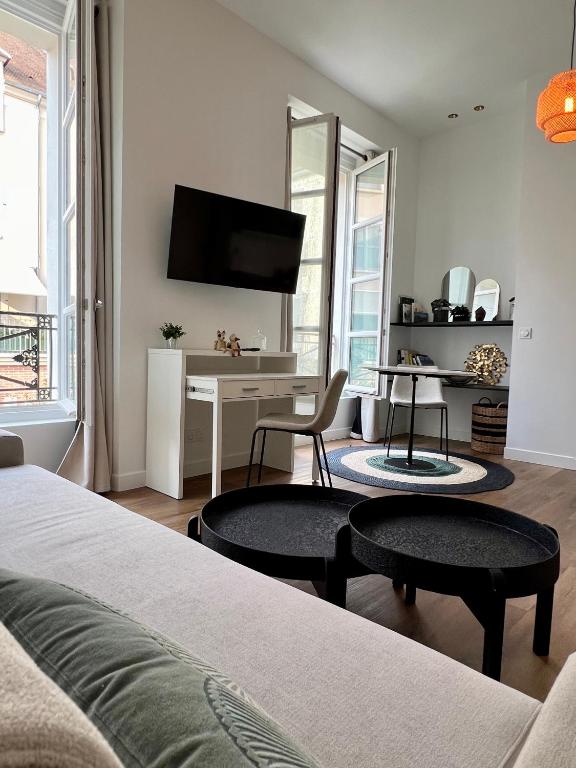 a bedroom with a bed and a desk with a television at Le Laurencin Sens - Le Zen - Cœur de ville in Sens