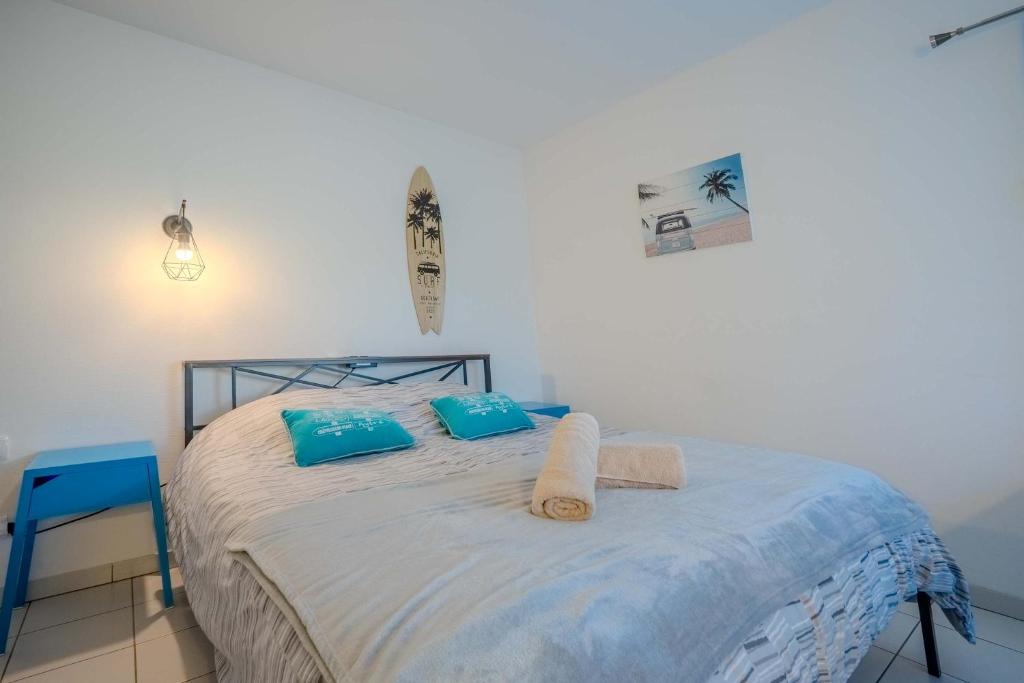 a bed with blue pillows and towels on it at Appartement Dauphin - Résidence Kiwi in Aytré