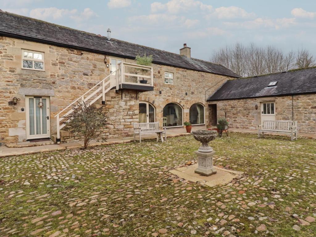 een oud stenen gebouw met een binnenplaats met een vogelbad bij The Classic in Falstone