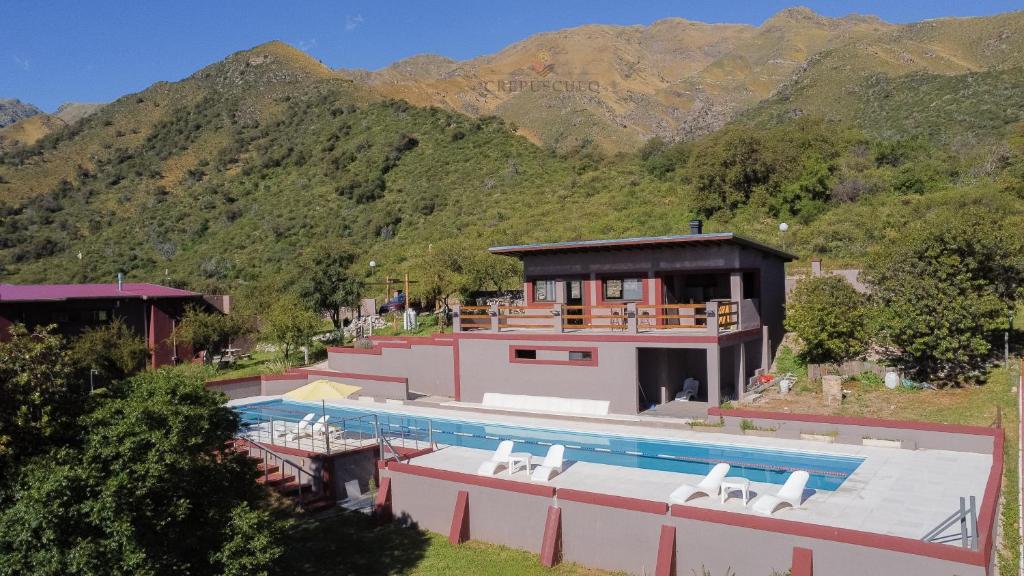 een huis met een zwembad voor een berg bij Crepúsculo Serrano in Merlo