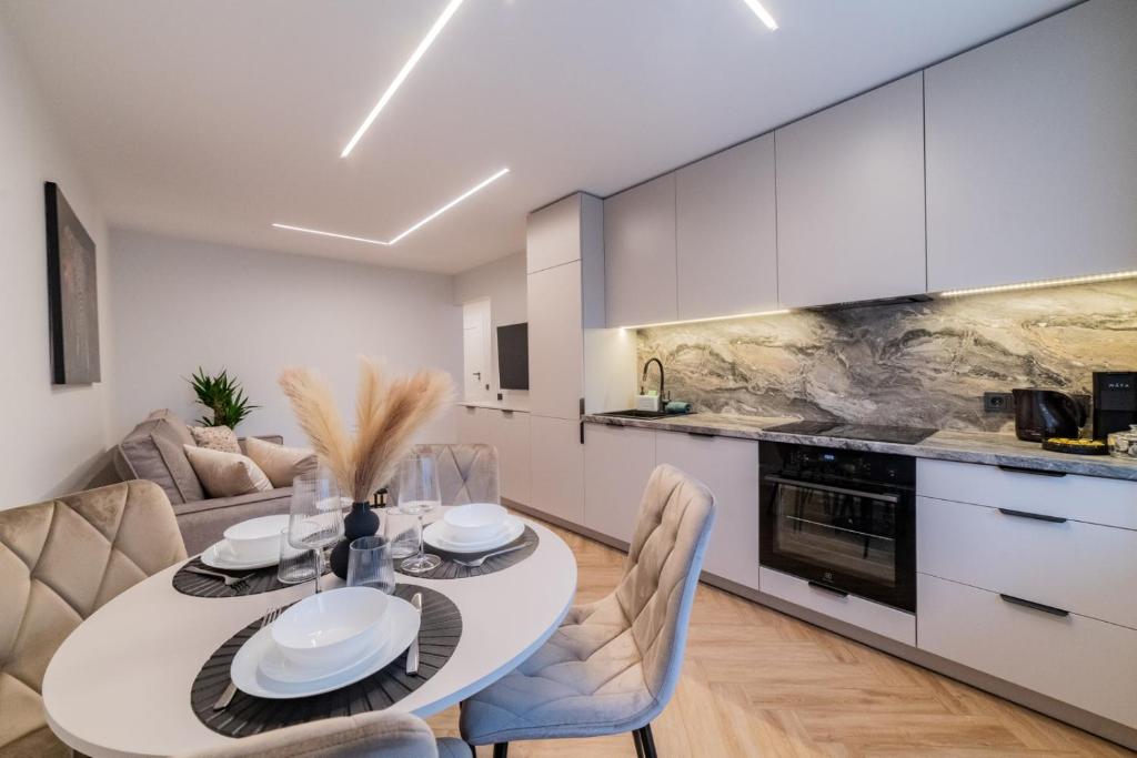 een keuken en eetkamer met een witte tafel en stoelen bij ENZO Apartments in Šiauliai