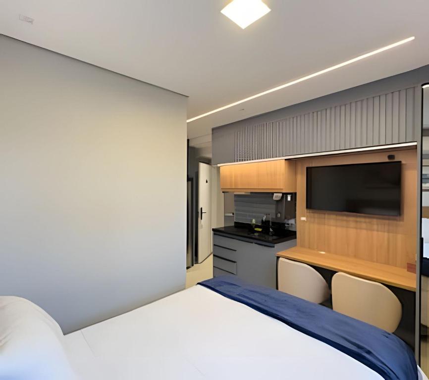 a bedroom with a large bed and a flat screen tv at Studio Moderno com Piscina a 15min a pé do Nubank Parque-117 in São Paulo