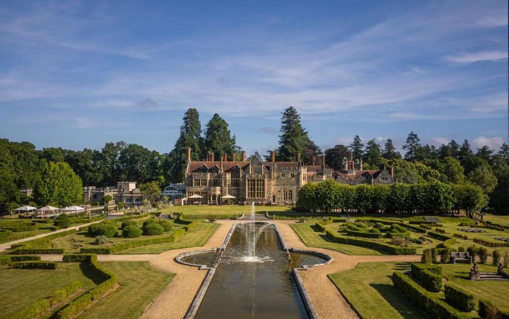 a large house with a fountain in front of a garden at Rhinefield House Hotel in Brockenhurst