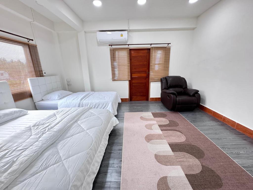 een slaapkamer met 2 bedden, een stoel en een tapijt bij Sun Sun Hostel in Pai