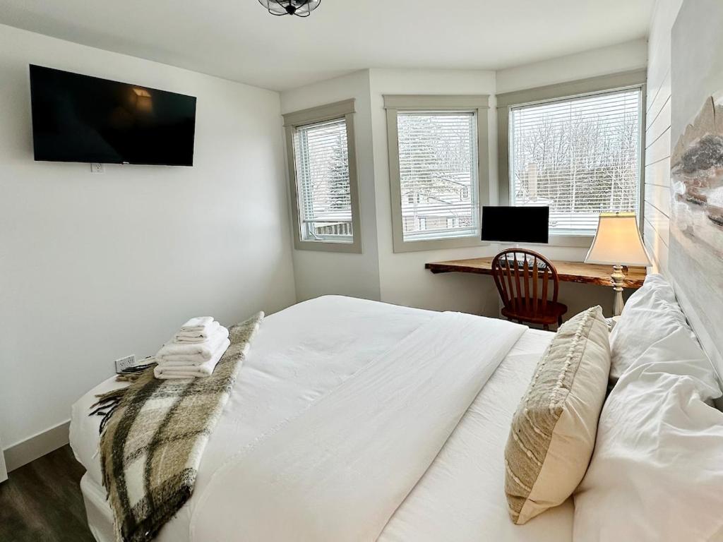 a bedroom with a white bed with a desk and windows at Pony Trail in Collingwood