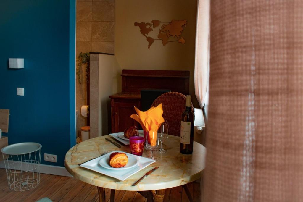 een tafel met een bord eten en een fles wijn bij Au Vent des Blés in Incourt