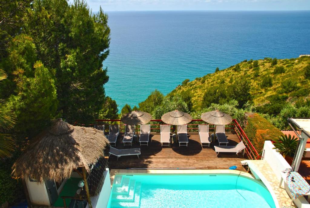 Una piscina con sillas y sombrillas y el océano. en Villa Giulia con piscina vista mare, en Sperlonga