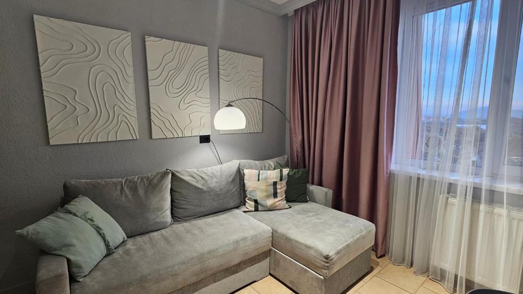 Una sala de estar con un sofá y una ventana. en Blue Apartment, en Mukácheve