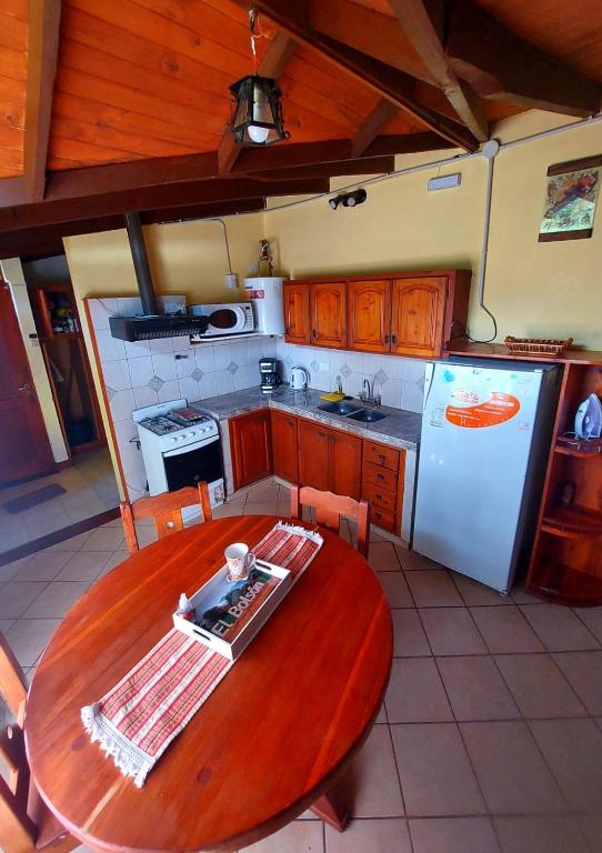 a kitchen with a wooden table and a white refrigerator at CASA los ciruelos in El Bolsón