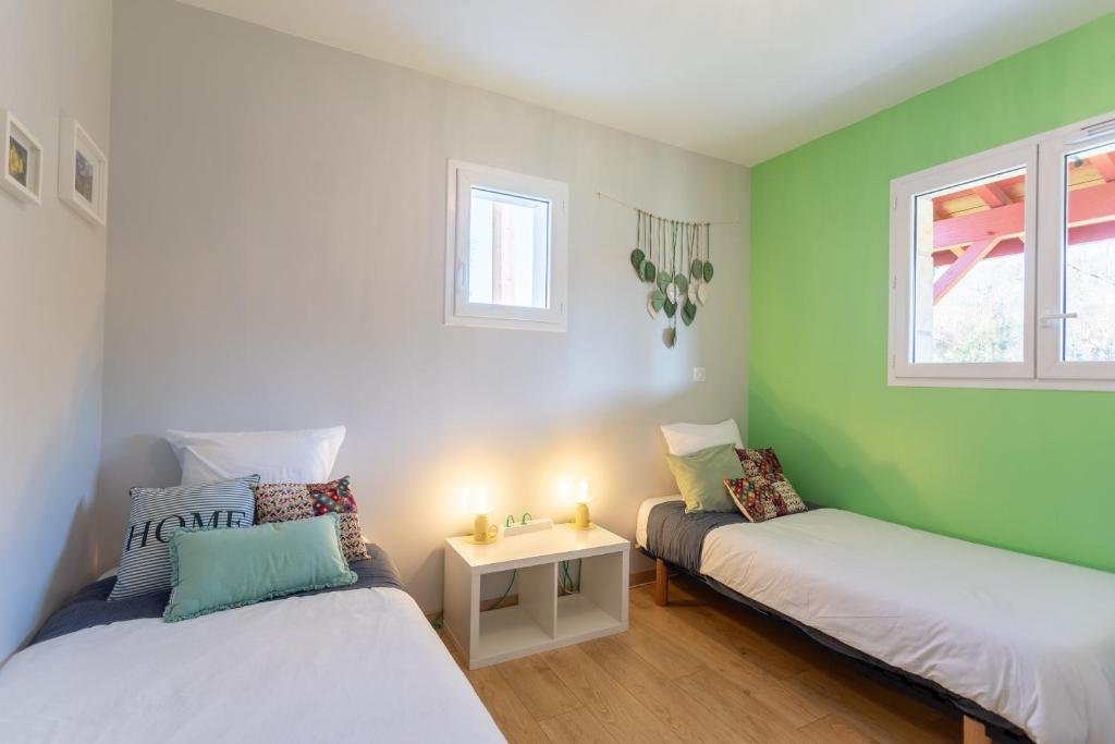 Dos camas en una habitación con paredes verdes. en Chambre - Dorine, en Aroue