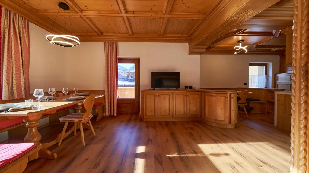 a dining room with a table and a television at Sappada Family Apartments in Sappada