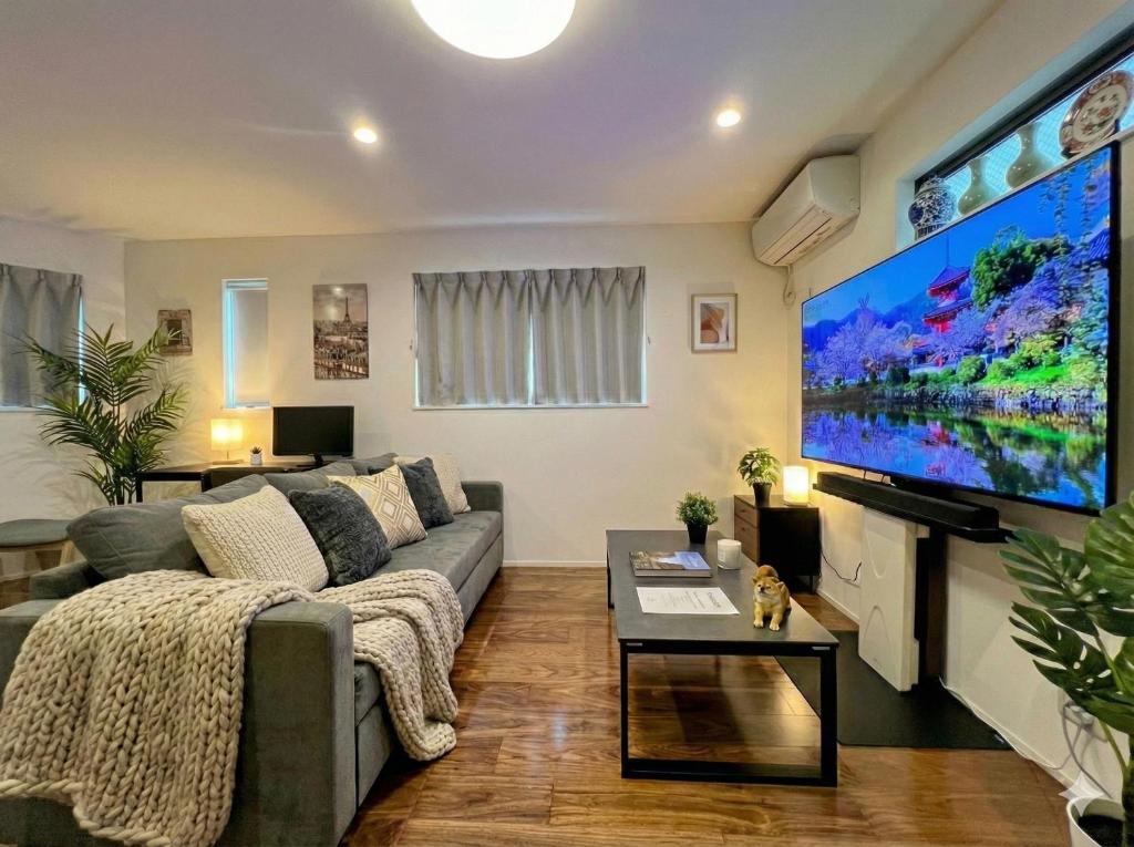 a living room with a couch and a large screen tv at Brand New Modern Haven 7-Min Walk to Shinkoenji Station 9-Min Train to Shinjuku in Tokyo