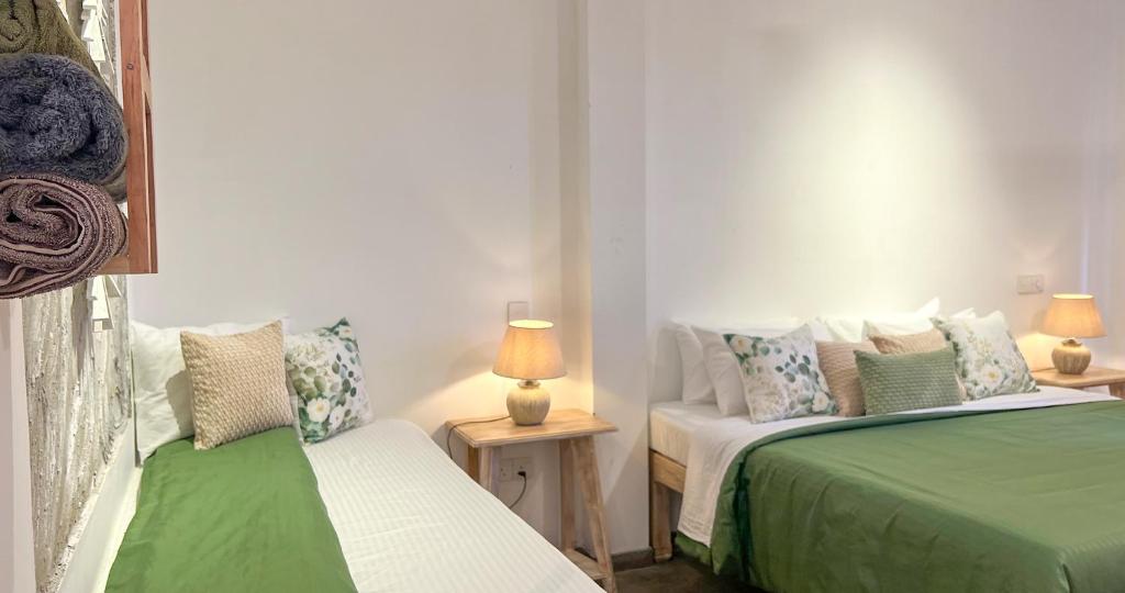 ein Schlafzimmer mit zwei Betten und zwei Tischen mit Lampen in der Unterkunft Pine Cone Cottages, Ella in Ella