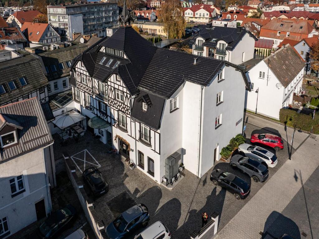 Una vista aérea de una casa blanca con autos estacionados en un estacionamiento. en Hotel Rejs, en Ustka
