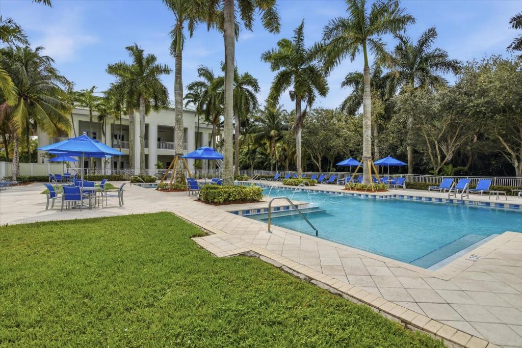 ein Resort-Pool mit blauen Stühlen und Sonnenschirmen in der Unterkunft Spacious 1BR Loft Villa - Pool Golf - Doral Downtown in Miami