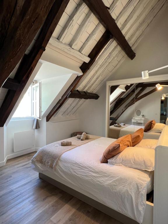 two beds in a bedroom with wooden ceilings at Le Laurencin Sens - Le Comble - Cœur de ville in Sens