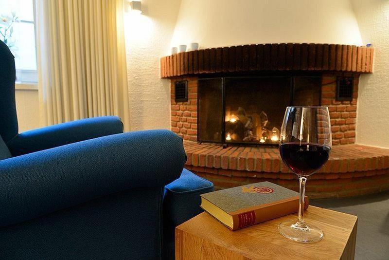 ein Glas Wein und ein Buch auf dem Tisch mit Kamin in der Unterkunft Heideblick - Tagungs- und Freizeithotel an der Lüneburger Heide in Jesteburg