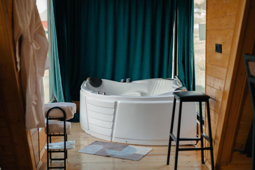 baño con bañera blanca y 2 taburetes en Vista cottage, en Kazbegi
