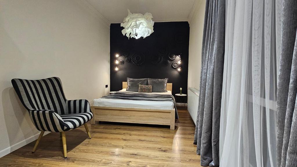 a bedroom with a bed and a chair and a chandelier at Black Room Apartment in Mukacheve
