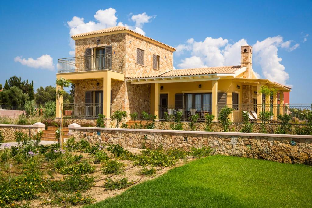 una casa con una pared de piedra y césped verde en Orion Luxury Villa en Svoronata