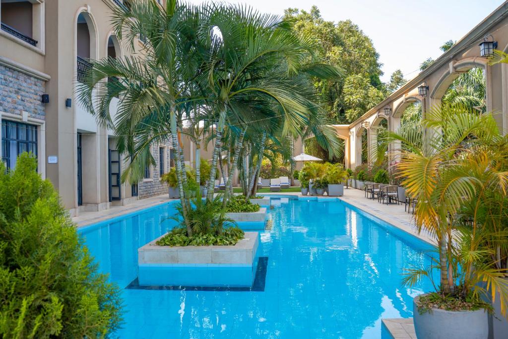 Una piscina con palmeras al lado de un edificio. en Fontis Residences Hotel, en Kampala