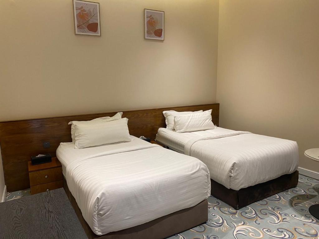 zwei Betten in einem Hotelzimmer mit weißer Bettwäsche in der Unterkunft Saaf hotel in Al Ghuţghuţ