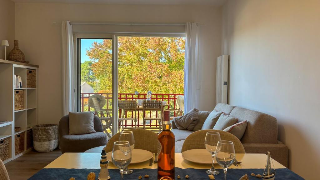 Una sala de estar con un sofá y una mesa con copas de vino. en T2, 50 m beach, balcony with sea view, en La Teste-de-Buch