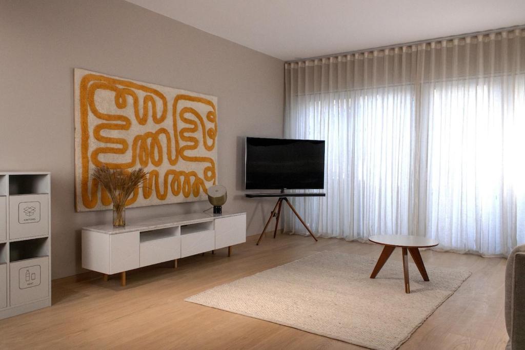 ein Wohnzimmer mit Flachbildfernseher und Tisch in der Unterkunft Modern Japandi retreat in Stockholm in Stockholm