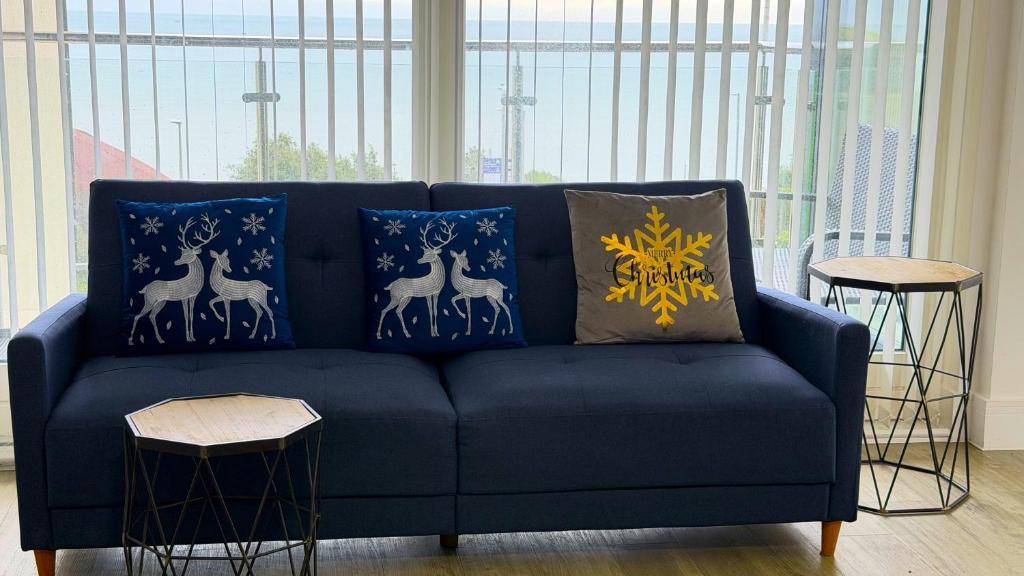 un divano blu con cuscini blu e oro di Seaview West Coast - Exceptional - 2 Bedrooms Sleeps 5 -Stunning Sea Views - 500 metres to Beach a Bournemouth