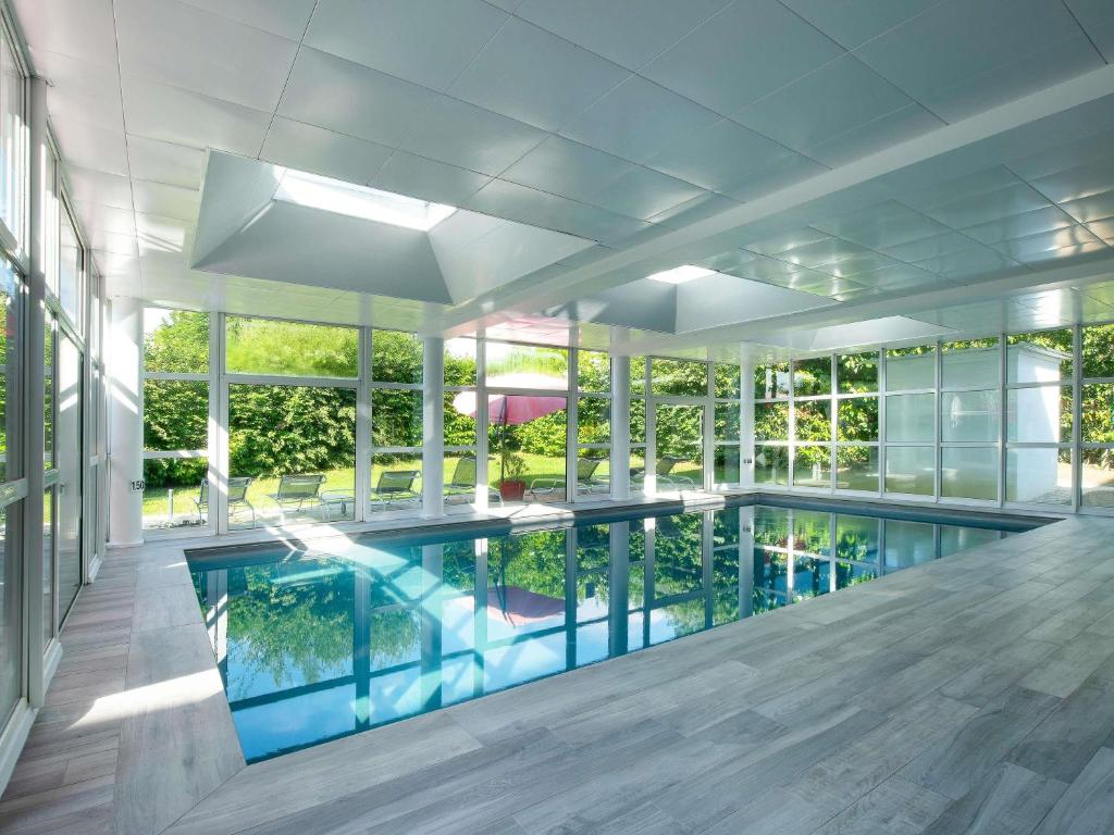 ein großes Schwimmbad in einem Gebäude mit Fenstern in der Unterkunft Novotel Senart Golf De Greenparc in Saint-Pierre-du-Perray