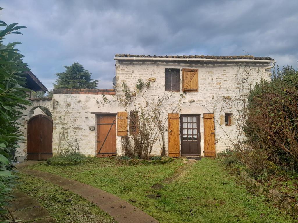 an old white building with wooden doors on a yard at Gîte des Fraignaies in Saint-Juire-Champgillon