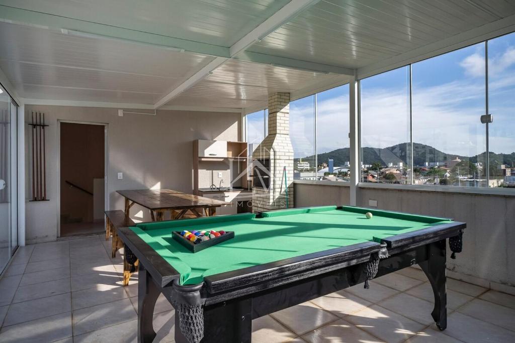 einen Billardtisch in einem Zimmer mit einem großen Fenster in der Unterkunft Cobertura 07 Antares Bombinhas in Bombinhas