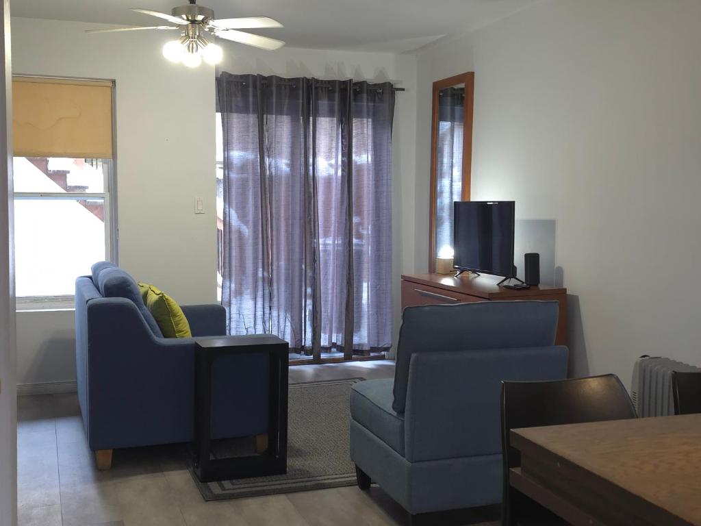 a living room with two blue chairs and a tv at STUDIO SAINT-ROCH in Quebec City