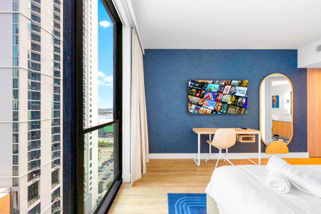 een slaapkamer met blauwe muren en een groot raam bij Luxury Studio & City Views in Miami