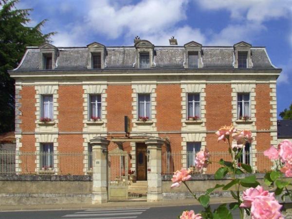 ein großes Backsteingebäude mit rosa Blumen davor in der Unterkunft La Renaudière in Chenonceaux