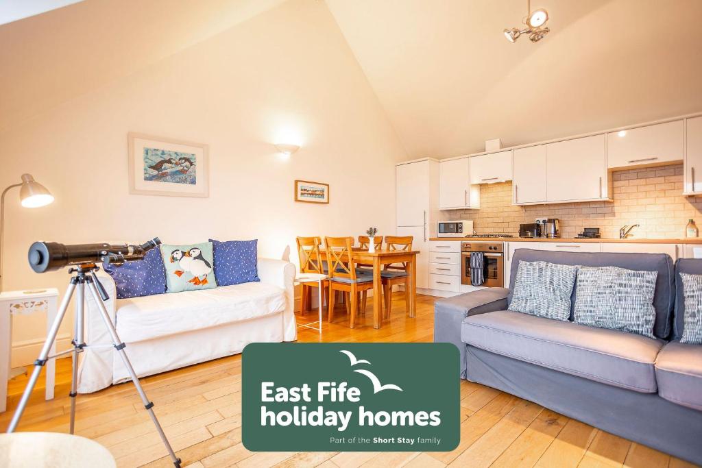 een woonkamer met een bank en een camera bij Coastal View - St Monans in Saint Monance