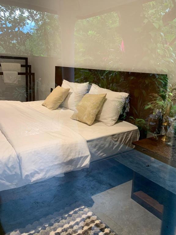 a bedroom with a bed with white sheets and pillows at Elephant Trail Homestay in Habarana