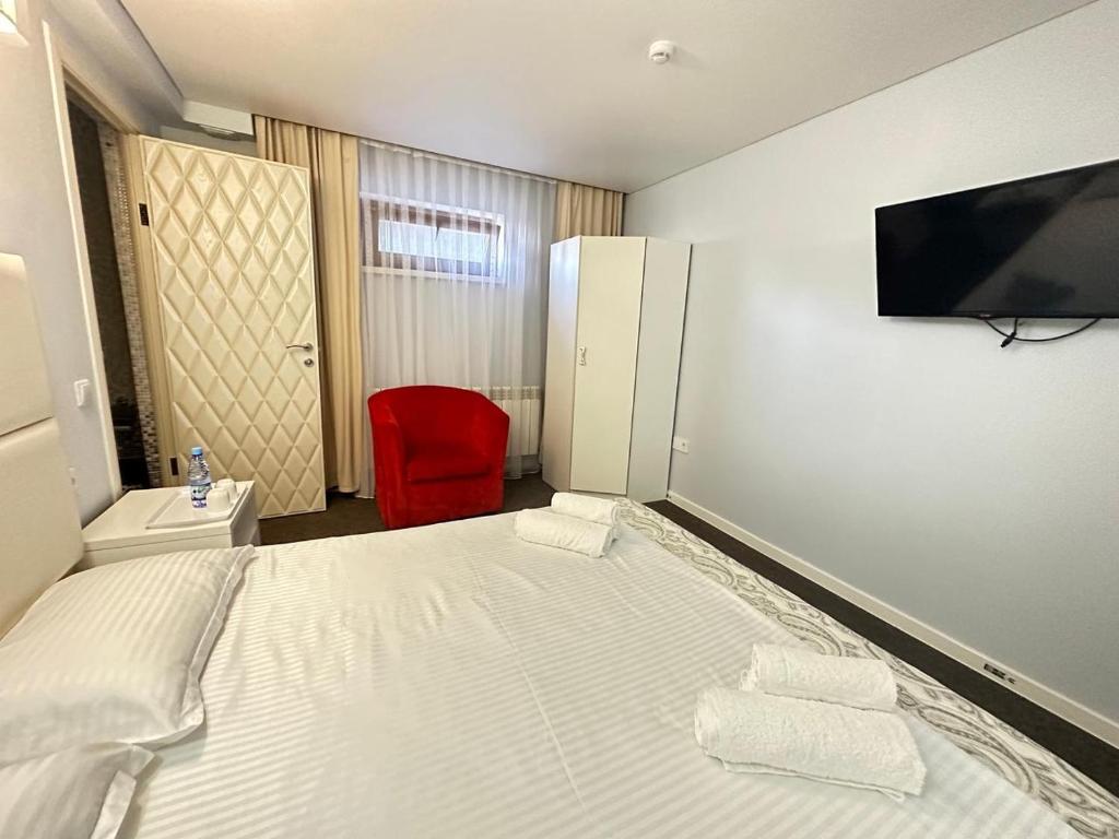a bedroom with a white bed and a red chair at Baiterek Сарайшык 40 in Astana