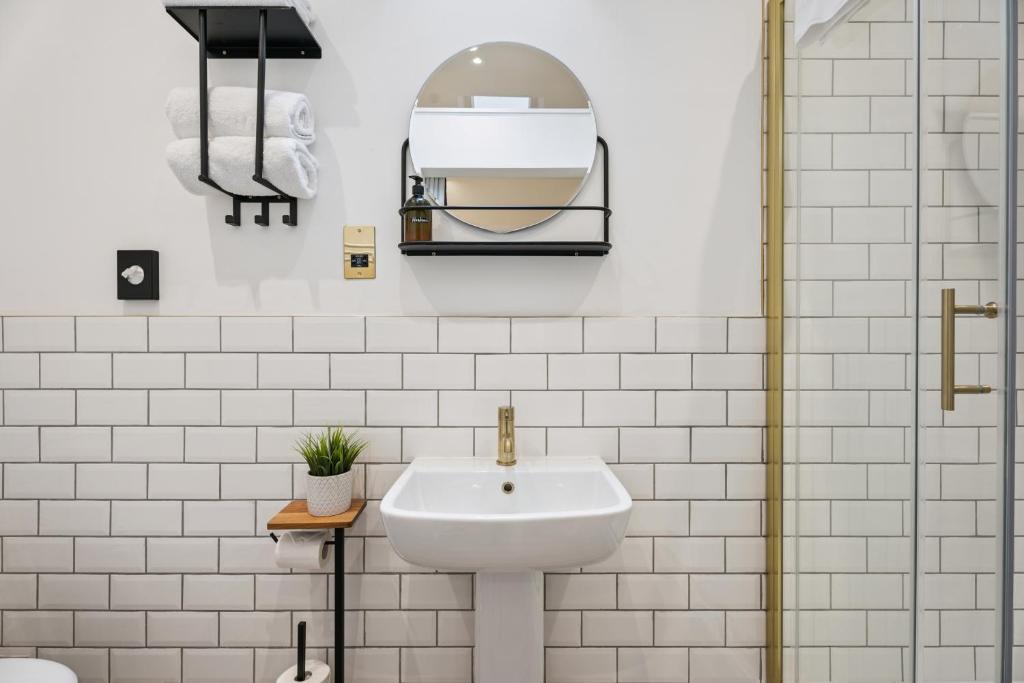 Un baño blanco con lavabo y espejo. en Flower Pot Hotel, en Henley on Thames