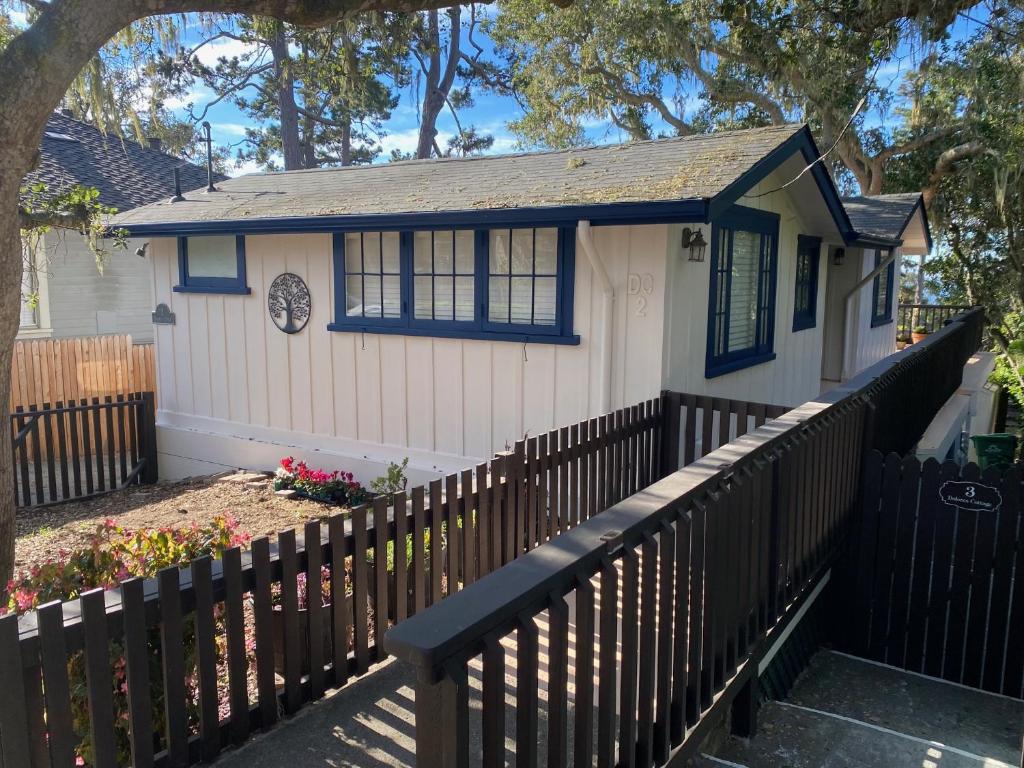 een klein wit huis met een zwart hek bij Carmel Dolores Cottages in Carmel