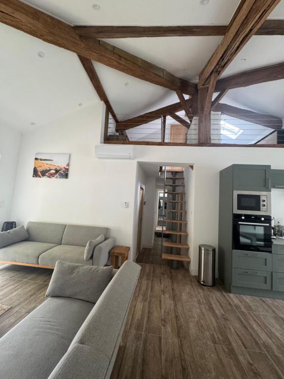 een woonkamer met een bank en houten vloeren bij L'orangerie in Seignosse