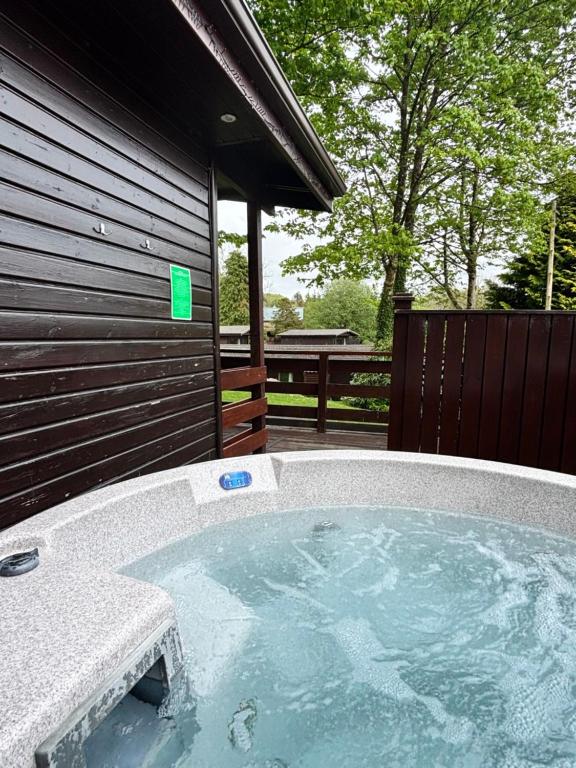 un jacuzzi en el patio trasero de una casa en Birch Lodge 13 with Hot Tub, en Newton Stewart