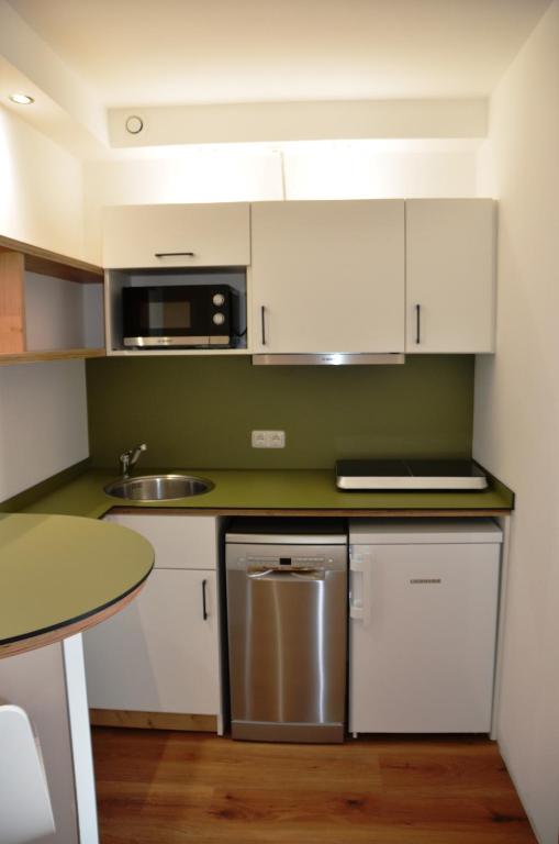 a kitchen with white cabinets and a stainless steel dishwasher at Wohnfakturei in Augsburg