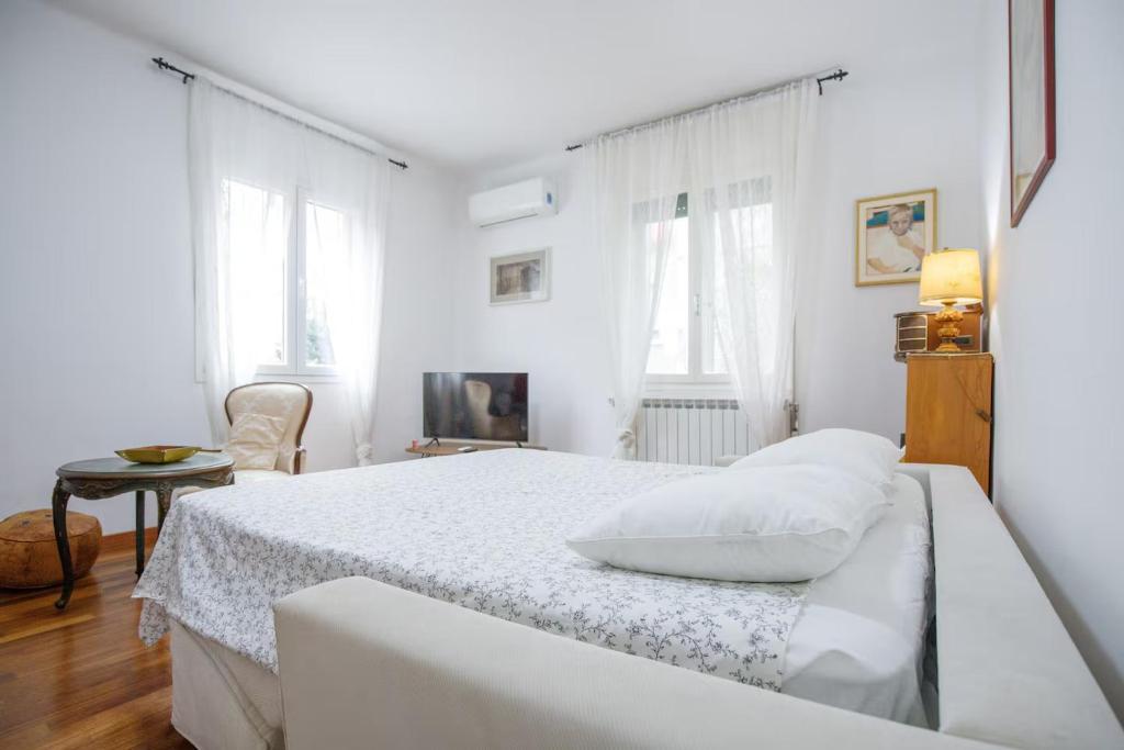 a white bedroom with a bed and a chair at Apartment with Free Parking Easy Access to Venice in Mestre